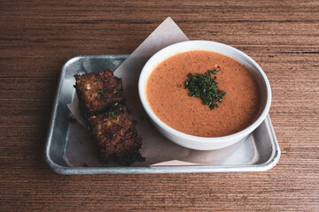Red pepper soup with chives and deep-fried cornbread on a tray