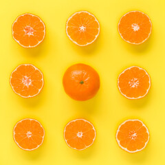 Fruit pattern of fresh mandarin slices on yellow background. Flat lay, top view. Pop art design, creative summer concept. Half of citrus in minimal style. Tangerine.