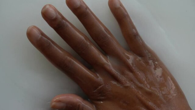 Dark skin hand in the milky smooth water substance