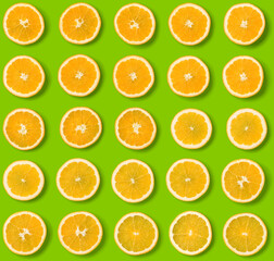 Seamless pattern of orange fruit slices on green background. Flat lay, top view. Food background. .  Pop art design, creative concept.