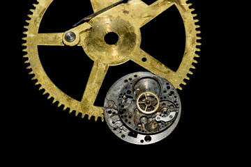 Obraz premium Closeup of antique watch parts in gold and silver on black needing repair.