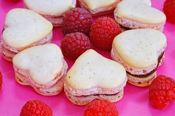 Pink heart shaped macaron cookies with fresh raspberries