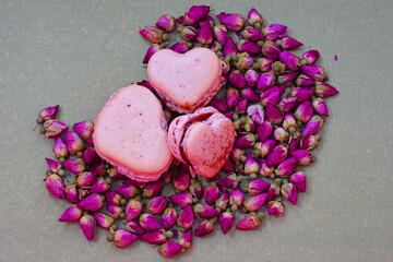 Pink heart homemade macaron cookies filled with raspberry jam for Valentines Day on a dried roses background