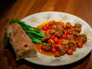 Meatballs with burst cherry tomatoes, broccoli, and crusty bread