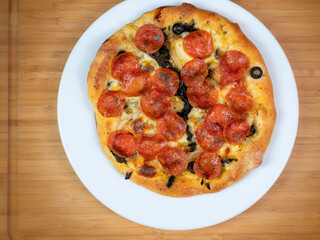 Homemade personal size pepperoni pizza on a white plate