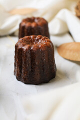 Caneles de bordeaux - traditional French sweet dessert serve with tea or coffee on wooden background.