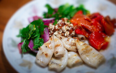 Salad dish with grilled squid, red peppers, onion, and greens