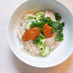 Homemade rustic-style chicken with rice, cilantro, cucumber, and peanut butter red pepper jelly sauce