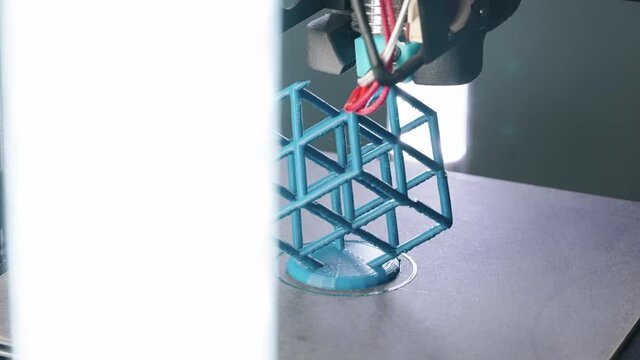 Close up of 3d Printer printing blue cube sculpture slow slider shot in 4k