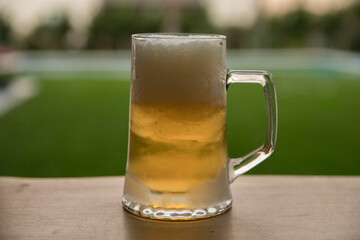 Alcoholic drinks. Closeup view of a golden cold beer in a glass mug on the pub table outdoors. 