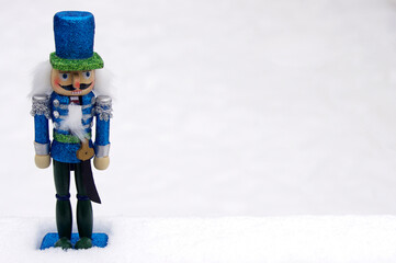 blue toy nutcracker in white snow with copy space