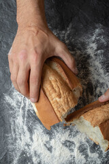 Female hand separate bread piece on flour background