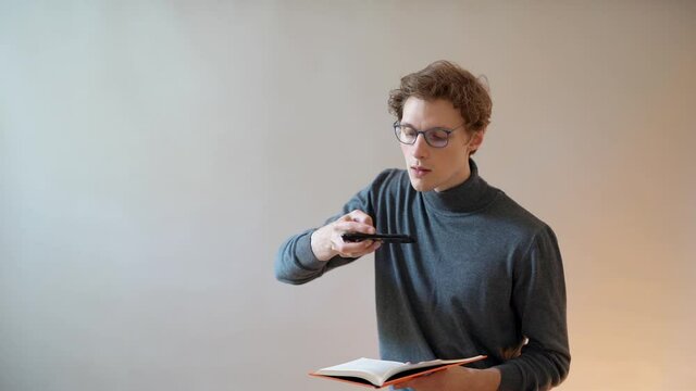 The guy with glasses takes pictures of the text of the book on a smartphone for digitization