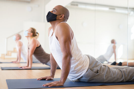 Group yoga session wearing protective masks at the fitness center