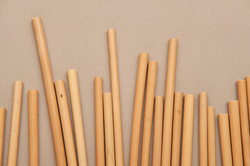 Bamboo Drinking Straw in Glass and Scattered on Table Isolated on beige Background Copyspace. Zero waste Reusable Bar Equipment for Drink Cocktails, Water or Lemonade