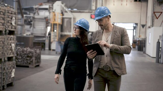 Mann f&uuml;hrt Frau durch Industriehalle