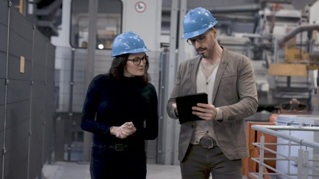 Mann f&uuml;hrt Frau durch Industriehalle