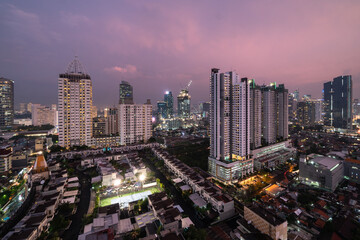 Fototapeta premium Sunset over Jakarta skyline where residential towers and houses contrast with modern office buildings in Java in Indonesia capital city
