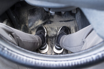 man sits in the car, view down, feet and pedals through the steering wheel