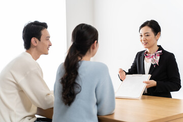 Obraz premium 会話をするアジア人カップル夫婦と営業する女性