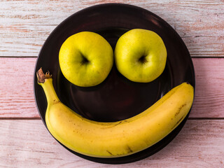 Apples and bananas in the shape of a face. Funny fruit picture.