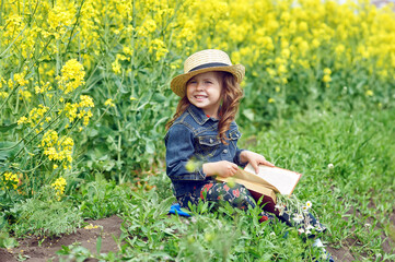 Portrait of a little girl with a book in nature . The concept of primary education