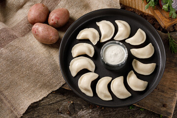 Appetizing traditional Russian dumplings, hand-made with potatoes. Still life on a wooden board. Close-up.
