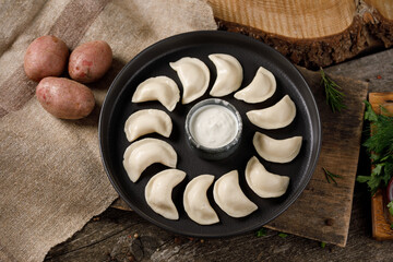Appetizing traditional Russian dumplings, hand-made with potatoes. Still life on a wooden board....