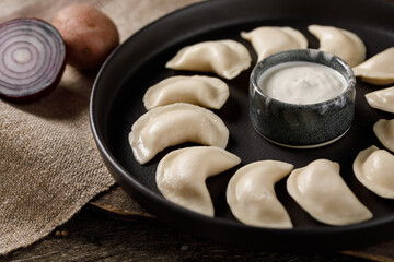 Appetizing traditional Russian dumplings, hand-made with potatoes. Still life on a wooden board. Close-up.