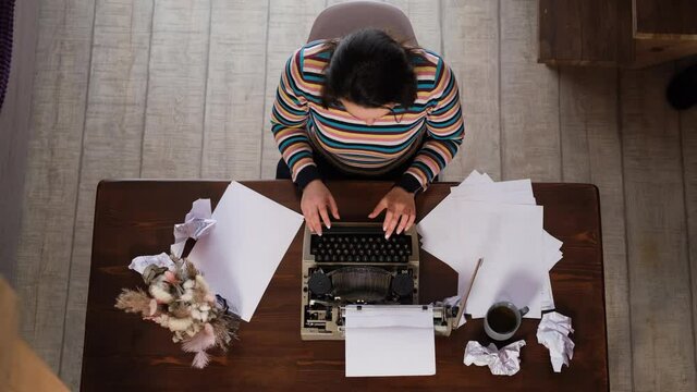 Female Sitting at Desk and Typing on a Typewriter Indoors. View from Above. Literature, Writing and Journalism Concept