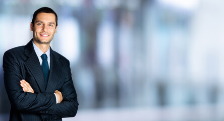 Portrait of happy confident businessman in black suit and blue tie, with crossed arms pose, copy...