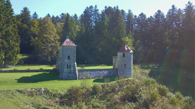 Cyclists Going Past Remains of Medieval Hunting Lodge In Masun. Aerial Dolly Back