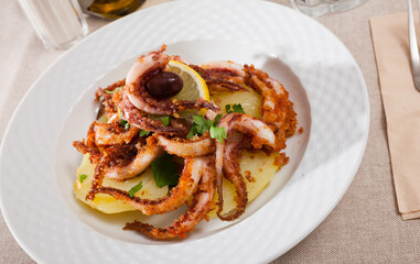 Delicious cooked squid or octopus tentacles with lemon and parsley on a plate. High quality photo