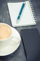 Smartphone, coffee with milk and notepad for notes. Work or relaxation with mobile phone