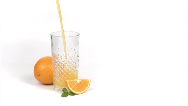 Pouring of fresh orange juice in glass on white background