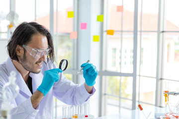 Asian smart pharmaceutical scientist feels happy with his new medical scientific research product, tablet pill in research laboratory. To make vaccine for treating Corona virus or Covid-19