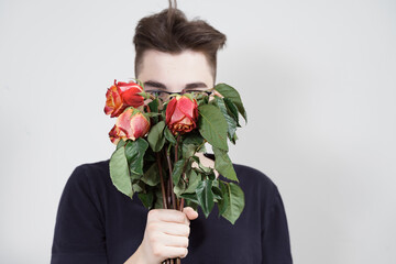 man is holding a bouquet of dead and withered flowers. focus on flowers, guy in blur.