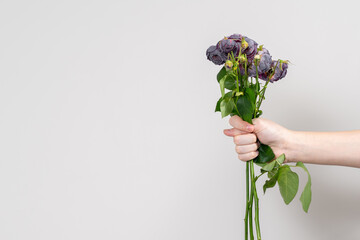 the man's hand holds out a bouquet of wilted flowers and shows a fig. copy spase