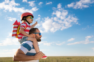 Father and son playing against blue summer sky background