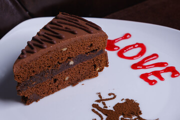 Delicious chocolate cake which lies on a plate with the inscription love