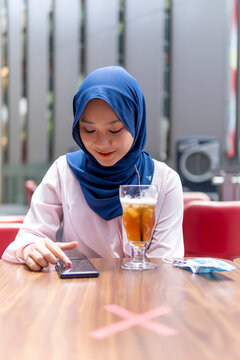 Cute Malay Girl at the coffee shop using smart phone