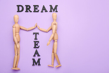 Wooden mannequins with words DREAM TEAM on color background