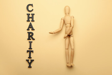 Wooden mannequin with word CHARITY on color background