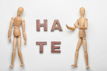 Wooden mannequins with word HATE on white background