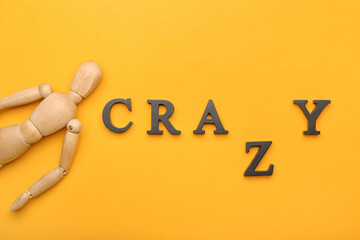 Wooden mannequin with word CRAZY on color background