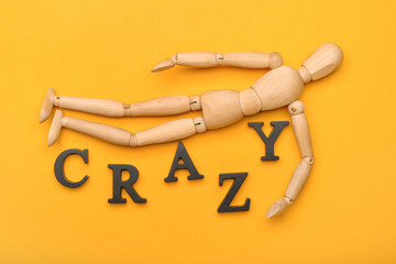 Wooden mannequin with word CRAZY on color background