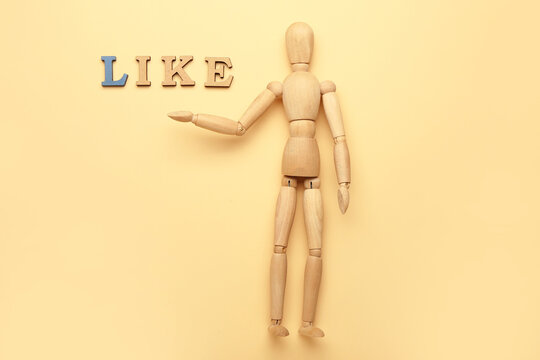 Wooden mannequin with word LIKE on color background