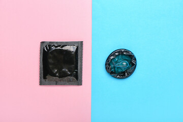 Wrapped and open condoms on color background