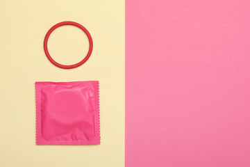 Wrapped condom and contraceptive ring on color background