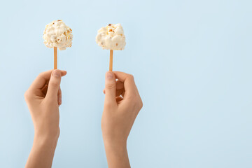Woman holding tasty popcorn balls on color background
